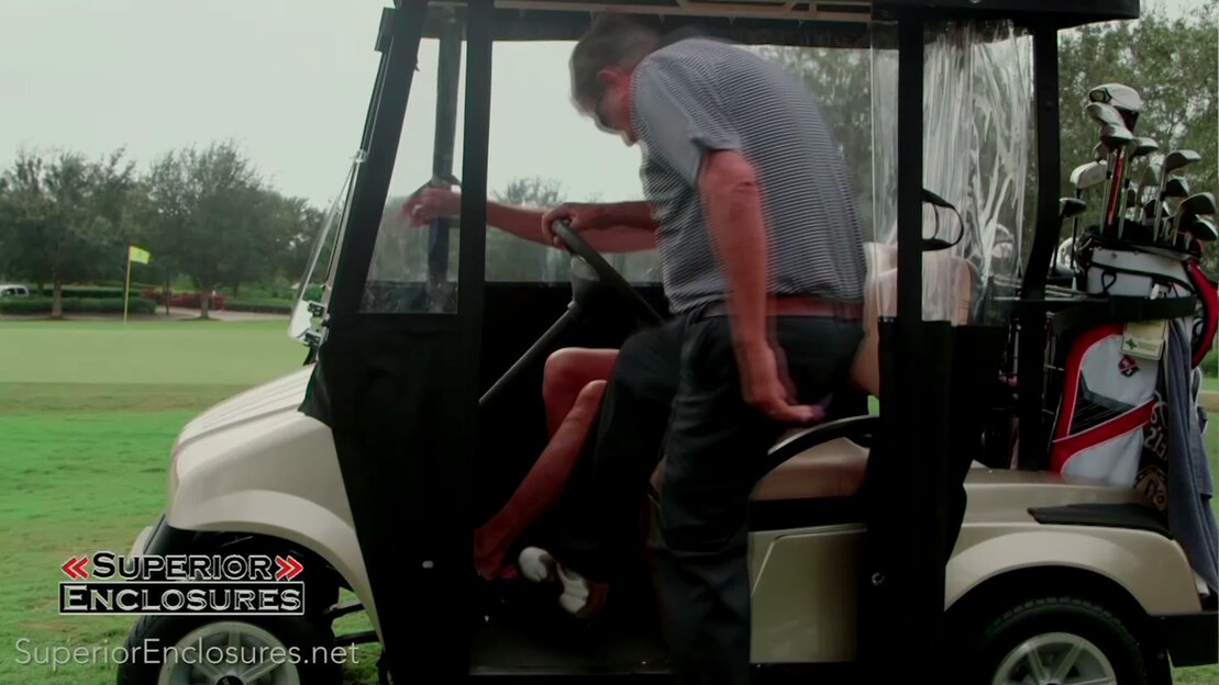Golfers staying dry inside cart enclosure on a rainy day